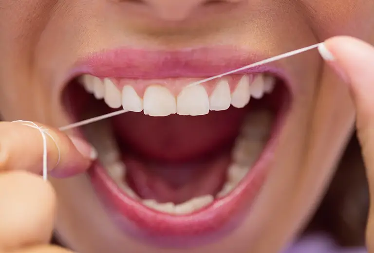 Close-up of female patient flossing her teeth